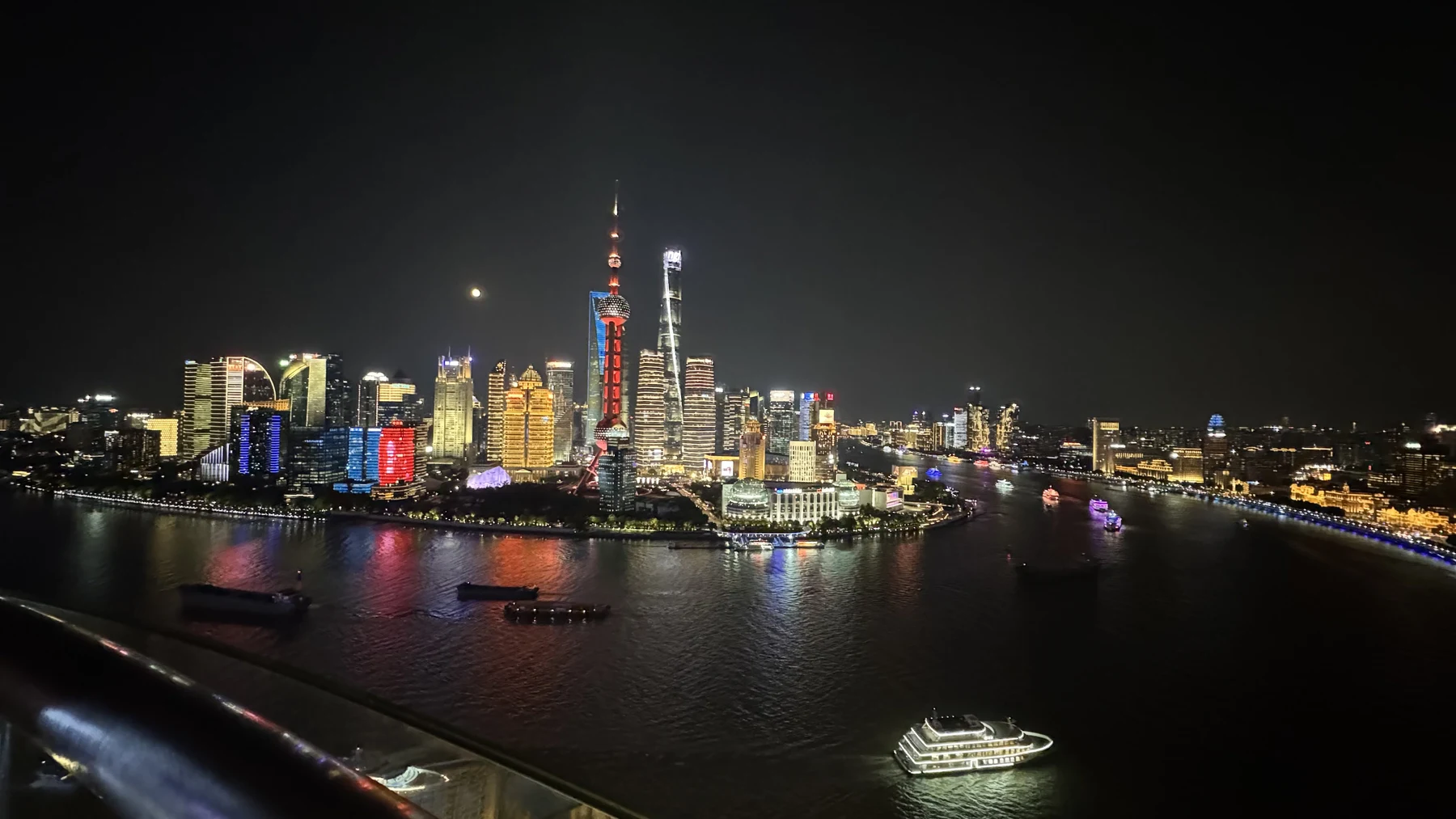 Shanghai skyline at night across the Huangpu River with the Oriental Pearl Tower lit in red